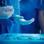 Surgeon being handed an instrument to close a wound