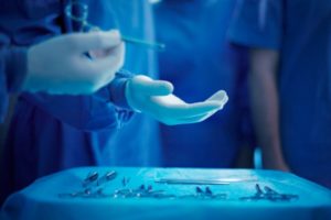 Surgeon being handed an instrument to close a wound